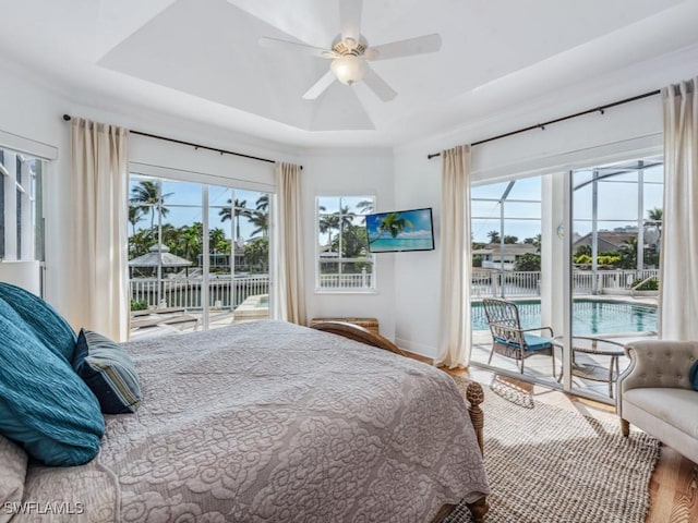 bedroom with access to exterior, wood-type flooring, a raised ceiling, and ceiling fan