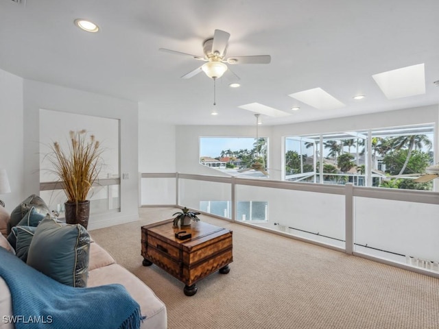 carpeted living room featuring a skylight and ceiling fan