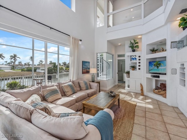 tiled living room featuring a water view, built in features, and a towering ceiling