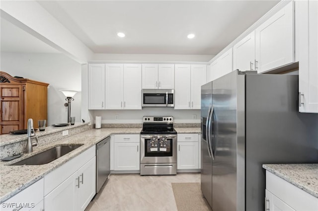 kitchen featuring sink, light tile patterned flooring, light stone counters, white cabinetry, and stainless steel appliances