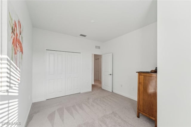 unfurnished bedroom with light carpet and a closet