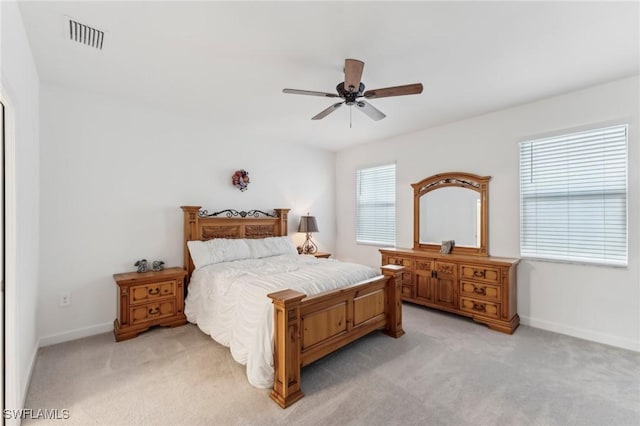 bedroom with multiple windows, light colored carpet, and ceiling fan