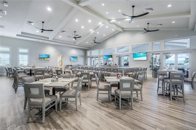 dining space with a wealth of natural light, beamed ceiling, high vaulted ceiling, and wood-type flooring