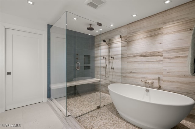 bathroom with shower with separate bathtub, tile walls, and tile patterned flooring