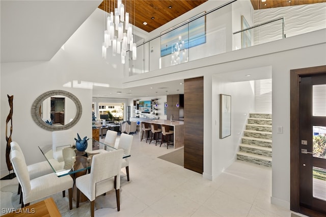 dining room featuring wooden ceiling, a high ceiling, light tile patterned flooring, and an inviting chandelier