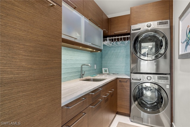 washroom featuring sink, cabinets, and stacked washer and clothes dryer