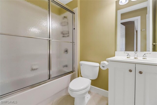 bathroom featuring toilet, shower / bath combination with glass door, vanity, baseboards, and tile patterned floors