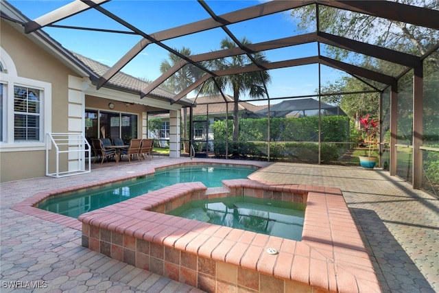 view of pool featuring glass enclosure, an in ground hot tub, and a patio