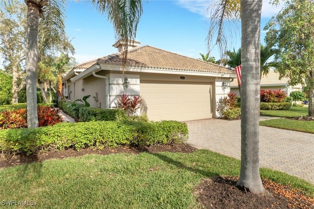 view of front of house featuring a garage, a front lawn, decorative driveway, and stucco siding