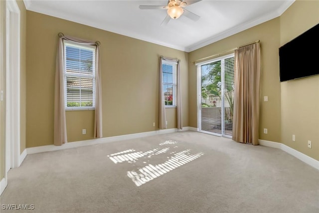 empty room with crown molding, baseboards, a ceiling fan, and light colored carpet