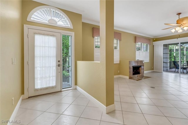 entrance foyer with light tile patterned floors, ceiling fan, a premium fireplace, and crown molding