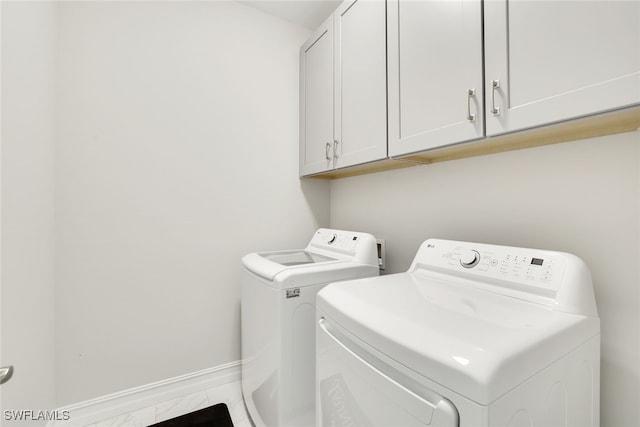 clothes washing area featuring cabinets and independent washer and dryer