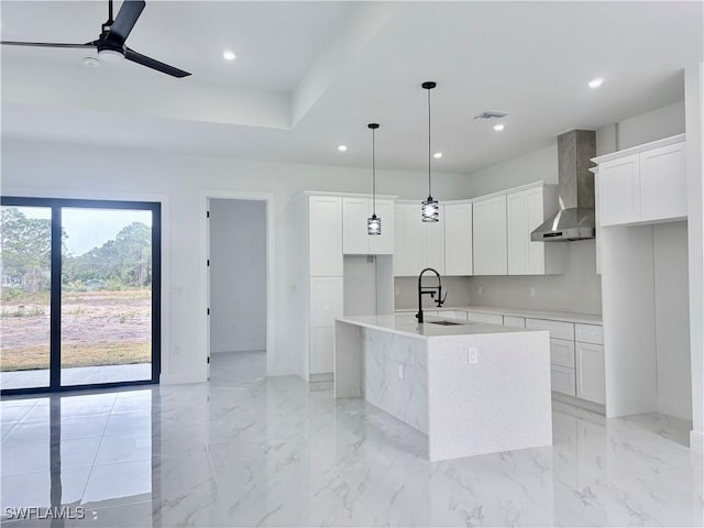 kitchen with white cabinetry, sink, wall chimney exhaust hood, and an island with sink