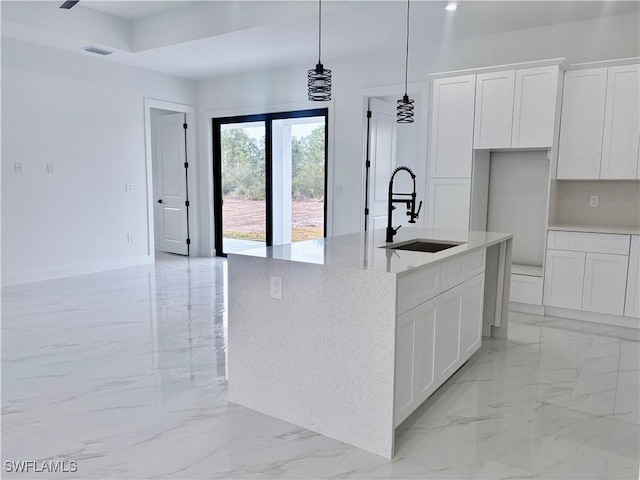 kitchen featuring sink, white cabinets, pendant lighting, and a center island with sink