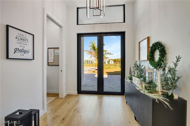 foyer entrance with light hardwood / wood-style flooring, a high ceiling, and a notable chandelier