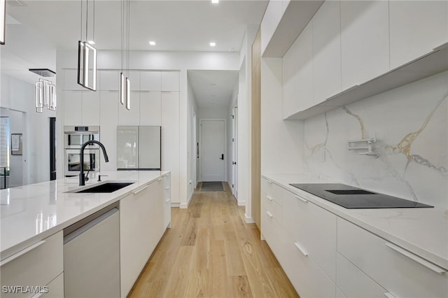 kitchen featuring white cabinetry, sink, dishwashing machine, and decorative light fixtures