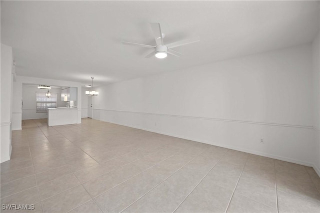 empty room featuring light tile patterned flooring and ceiling fan with notable chandelier