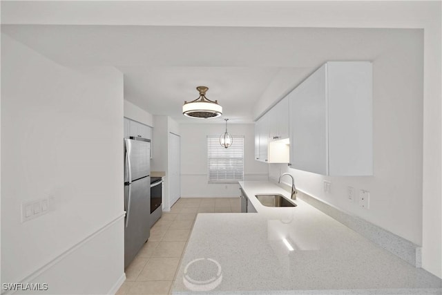 kitchen featuring appliances with stainless steel finishes, sink, pendant lighting, light tile patterned floors, and white cabinetry