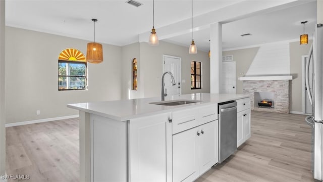 kitchen featuring sink, hanging light fixtures, light hardwood / wood-style flooring, an island with sink, and appliances with stainless steel finishes