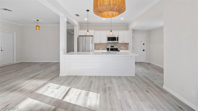 kitchen featuring appliances with stainless steel finishes, light wood-type flooring, backsplash, decorative light fixtures, and white cabinets