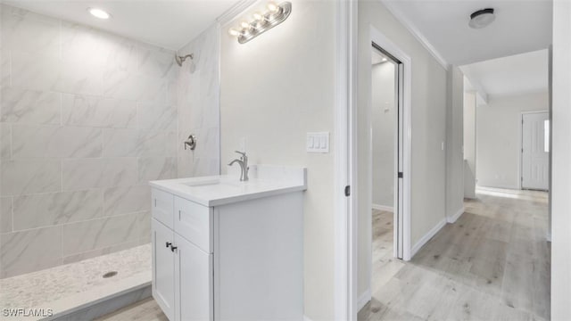 bathroom featuring a tile shower, vanity, and wood-type flooring