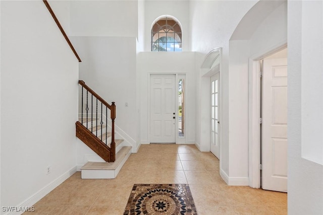 foyer entrance featuring a wealth of natural light, a towering ceiling, and light tile patterned flooring