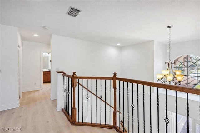 hallway with light hardwood / wood-style floors and an inviting chandelier