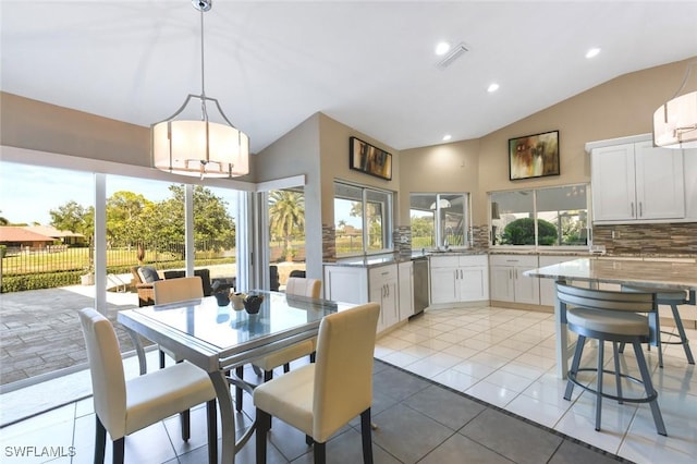 tiled dining space featuring sink and vaulted ceiling