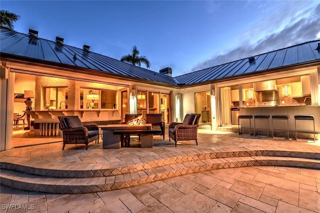 patio terrace at dusk with an outdoor bar and a fire pit