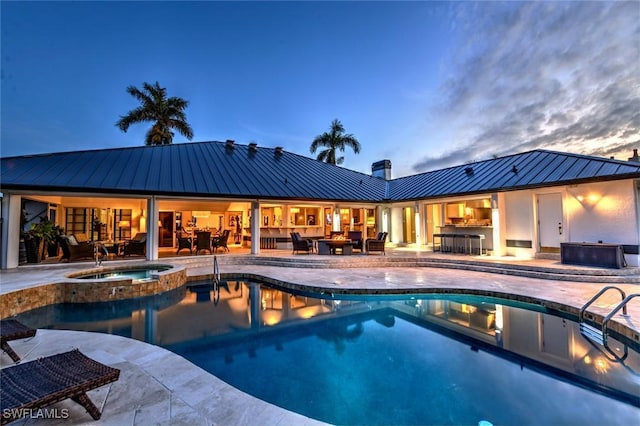 pool at dusk featuring an in ground hot tub, outdoor lounge area, and a patio area