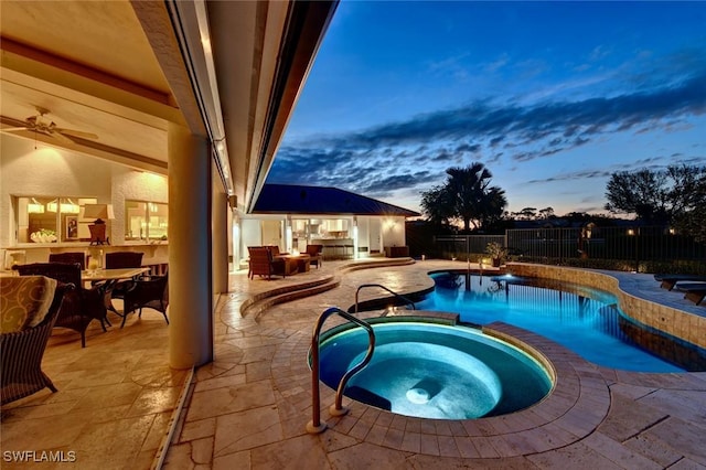 pool at dusk with a patio area and an in ground hot tub