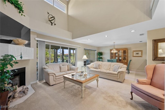 living room featuring light carpet, a high ceiling, and a notable chandelier