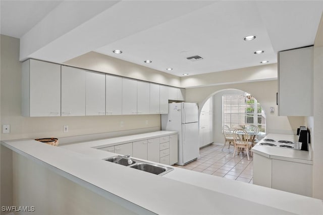 kitchen with light tile patterned floors, white fridge, white cabinetry, and sink