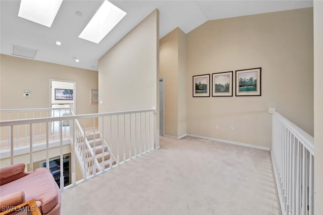 hall featuring vaulted ceiling with skylight and light colored carpet