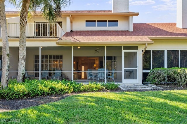 rear view of house with a balcony and a yard