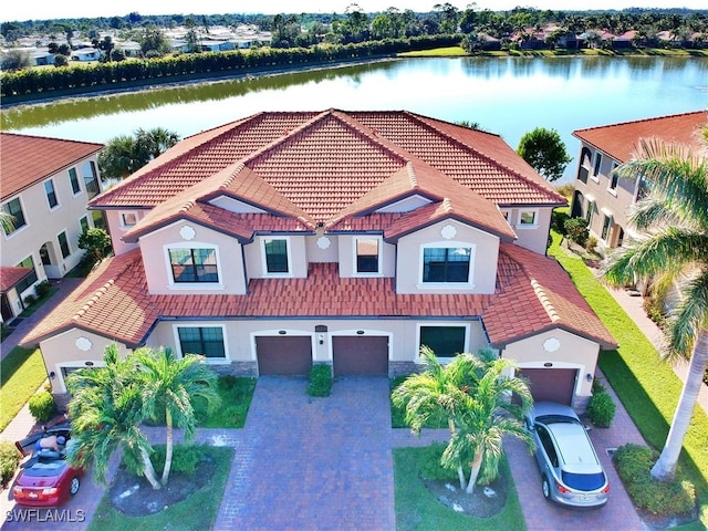 exterior space featuring an attached garage, stucco siding, and a water view