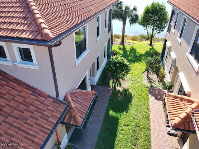 view of home's exterior featuring stucco siding, a tile roof, and a yard