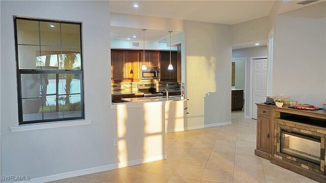 kitchen featuring appliances with stainless steel finishes, backsplash, sink, light tile patterned floors, and decorative light fixtures