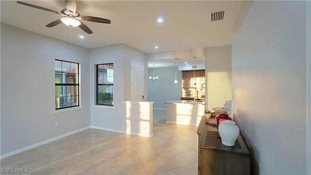 interior space with light tile patterned flooring and ceiling fan with notable chandelier