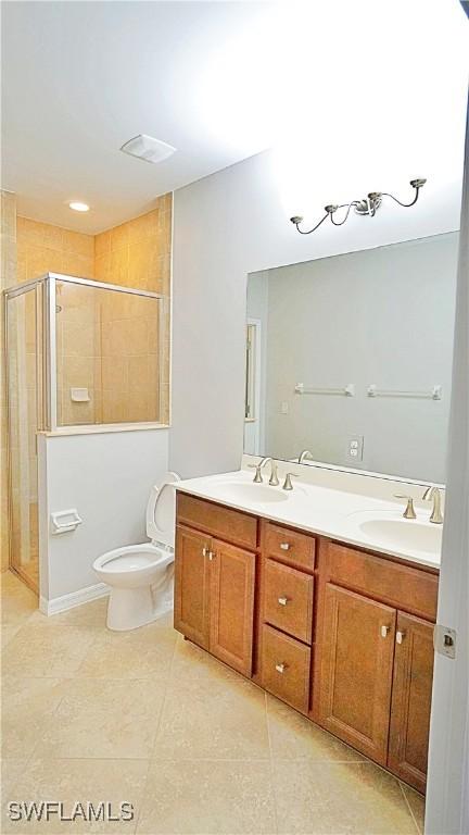 bathroom with tile patterned flooring, vanity, toilet, and walk in shower