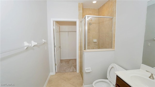 bathroom featuring tile patterned floors, a stall shower, a walk in closet, vanity, and toilet