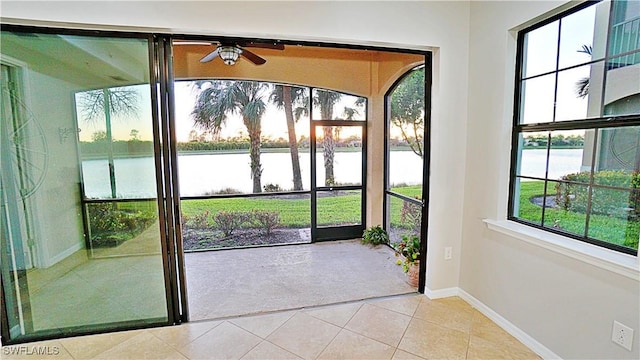 doorway to outside featuring light tile patterned floors, a water view, and ceiling fan