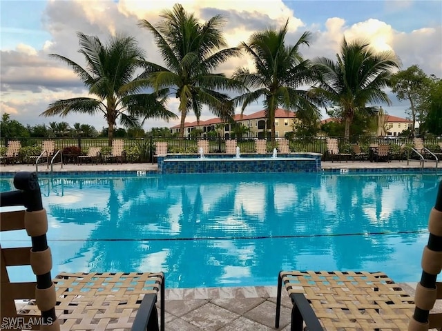 pool at dusk featuring pool water feature