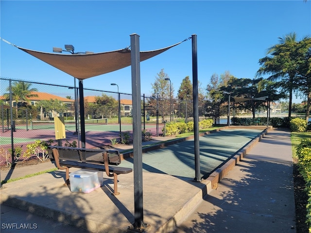 view of property's community with fence and a tennis court