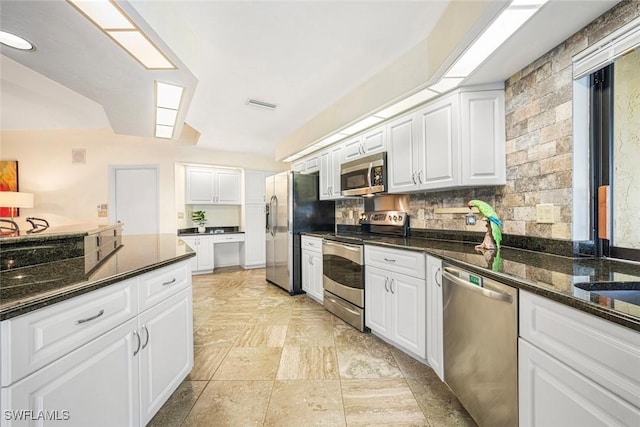 kitchen featuring dark stone counters, backsplash, white cabinetry, and stainless steel appliances