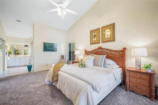 bedroom featuring ceiling fan, light carpet, high vaulted ceiling, and ensuite bath