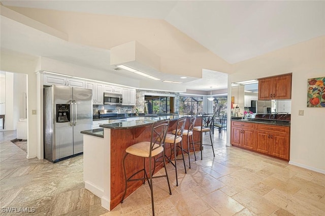 kitchen with white cabinets, a breakfast bar area, decorative backsplash, a kitchen island, and stainless steel appliances