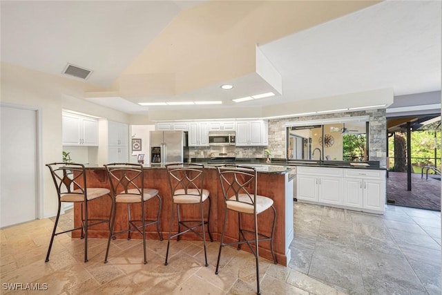 kitchen with white cabinets, stainless steel appliances, a spacious island, and a breakfast bar area