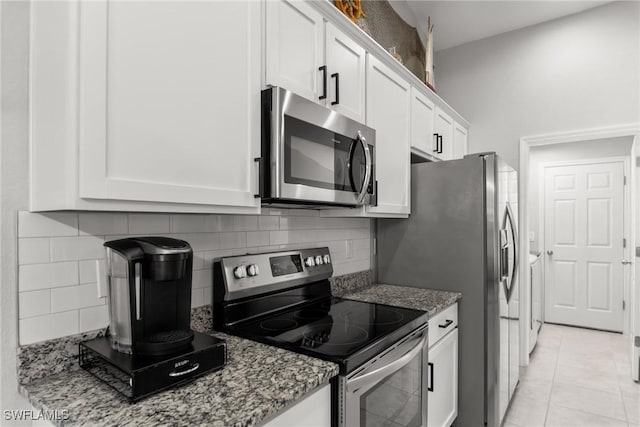 kitchen featuring stone counters, white cabinets, tasteful backsplash, light tile patterned flooring, and stainless steel appliances