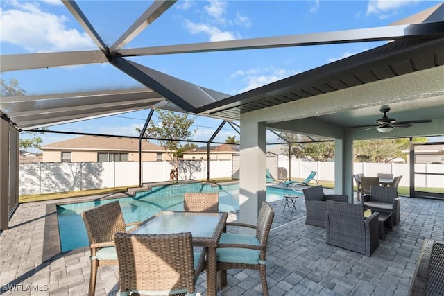 view of patio / terrace with a fenced in pool, glass enclosure, and ceiling fan